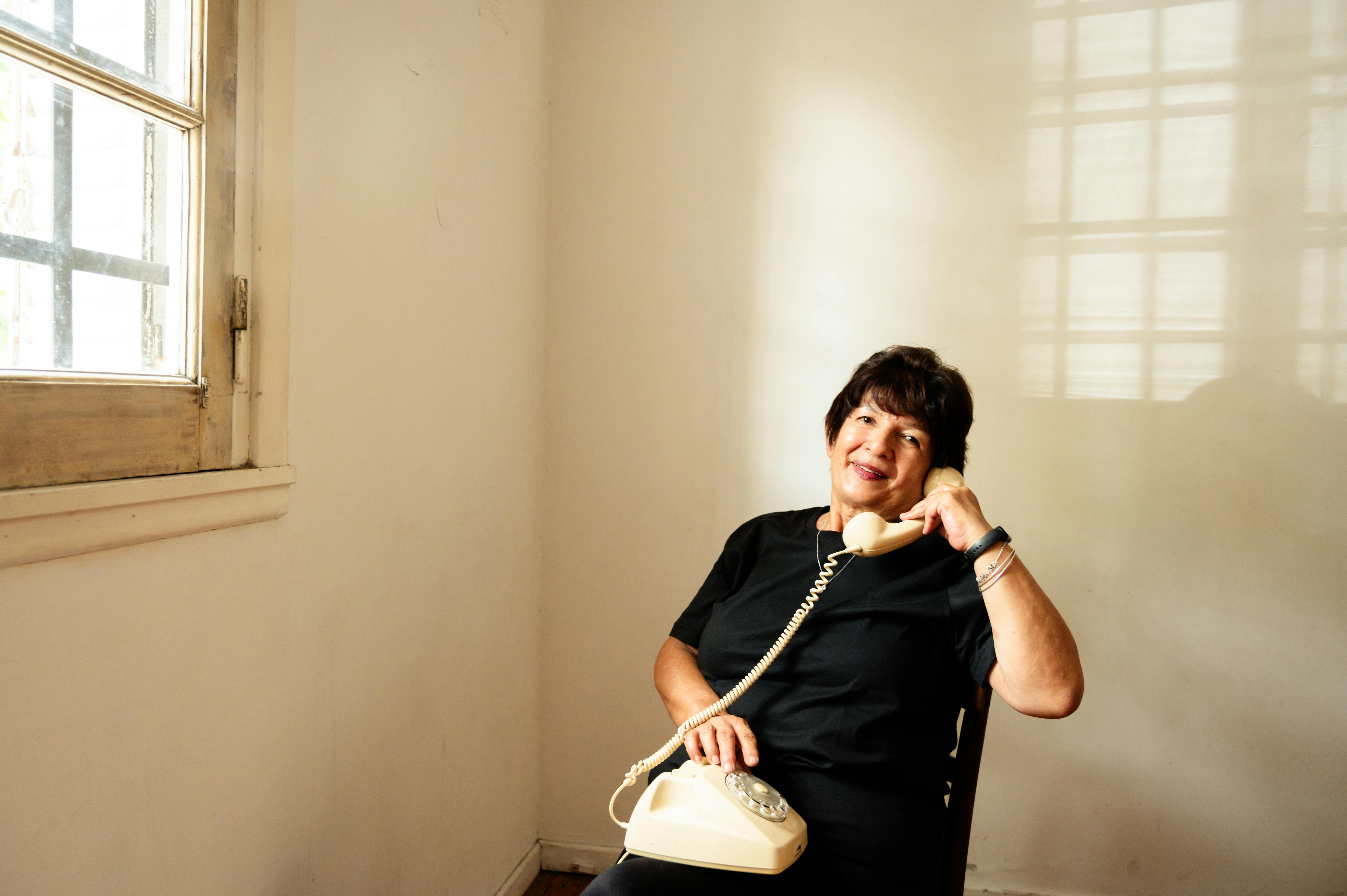 A senior woman sitting at a window, mid-conversation